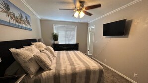 A bedroom with a bed, a ceiling fan, a TV mounted on the wall, and a window with blinds. - Updated, Comfortable and Luxury Stay in our 5 bedroom home.Close to Lagoon,Golf. (Woods Cross)