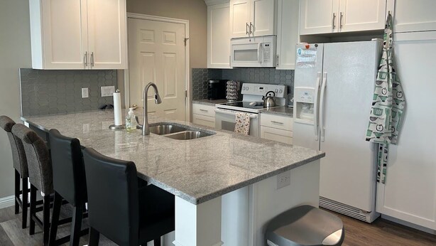 A modern kitchen with white cabinets, a granite countertop, a built-in oven, and a stainless steel sink. - Updated, Comfortable and Luxury Stay in our 5 bedroom home.Close to Lagoon,Golf. (Woods Cross)