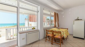 Un balcon avec vue sur la mer, une table avec des chaises et un réfrigérateur.