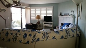 Una habitación acogedora con cama, televisor, una mesita y ventana con persianas.