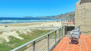 Un balcone con vista sulla spiaggia e sull'oceano, dotato di posti a sedere all'aperto e di un parapetto.