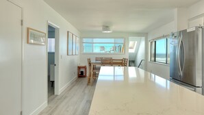 Una cucina moderna con un'isola grande, elettrodomestici in acciaio inossidabile e un'area pranzo con mobili in legno.