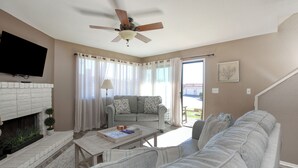Uma sala de estar com lareira, sofá, mesa de centro e ventilador de teto.