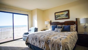 Quarto com uma cama grande, vista para a praia e um quadro na parede.