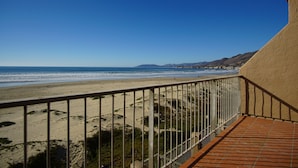 Uma varanda com vista para uma praia e montanhas ao longe.