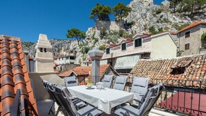 A terrace with a table and chairs, overlooking a historic town with stone buildings and a prominent tower. - Awesome home in Omis with house a mountain view (Omis)