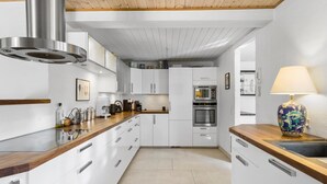 Una cucina moderna con mobili bianchi, elettrodomestici in acciaio inossidabile e un piano di lavoro in legno.