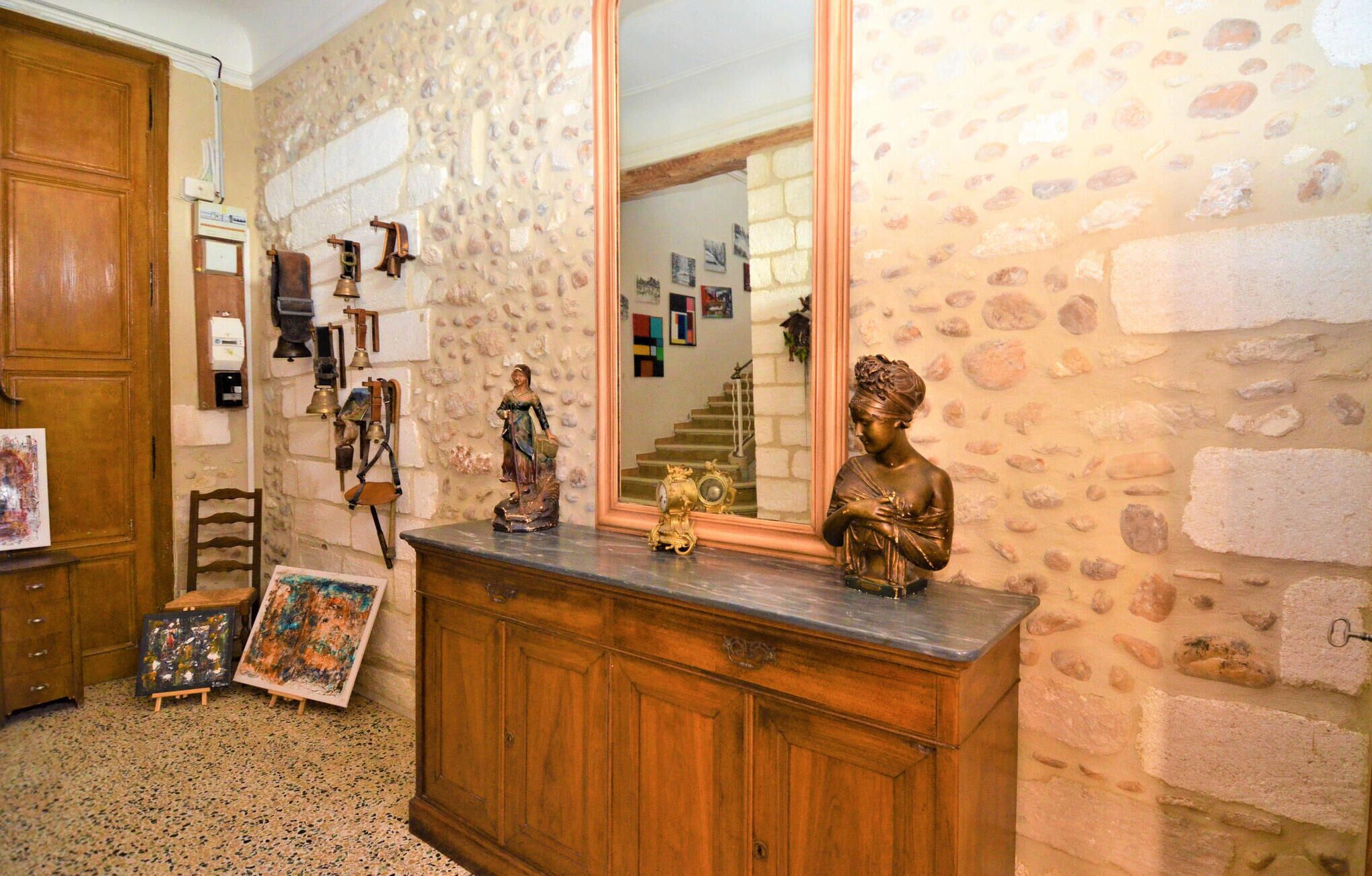 Ein Zimmer mit Steinwand, Holzschrank und einem Spiegel, der eine Treppe reflektiert.