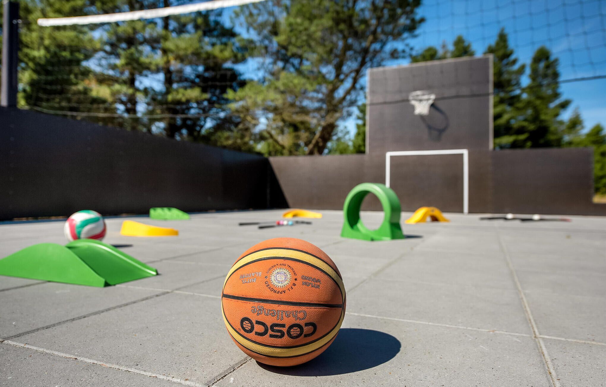 A basketball on a concrete surface with playground equipment in the background.