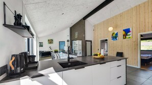 Eine moderne Küche mit einer großen Kochinsel, weißen Schränken und einer Wand mit Holzverkleidung.