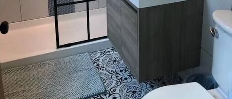 A modern bathroom with a shower enclosure, a vanity with a sink, and a toilet.