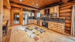 A log cabin kitchen with wooden cabinets, stainless steel appliances, and a wooden dining table. - THE LUXURY LODGE - SKI, RIDE, GOLF, BIKE, HIKE (Hunter)