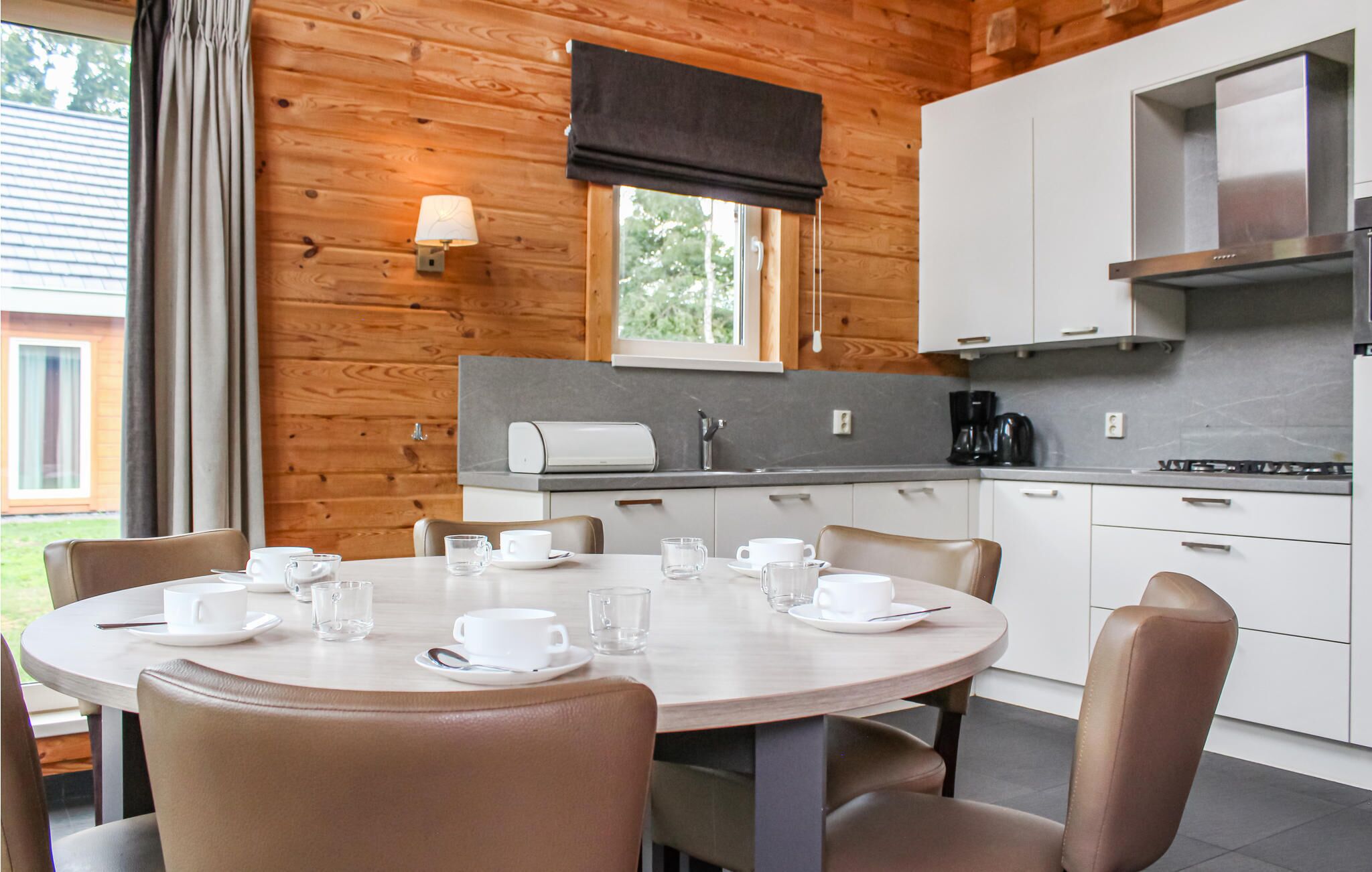 A modern kitchen with white cabinets, a built-in oven, and a coffee maker.