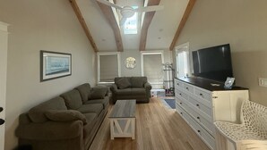 Ein Wohnzimmer mit einer Couch, einem Couchtisch, einem Fernseher und einem Sessel.