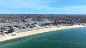 Eine Vogelperspektive zeigt eine Küstenlandschaft mit Strand, einer Marina und einem Wohngebiet mit Häusern und Straßen.