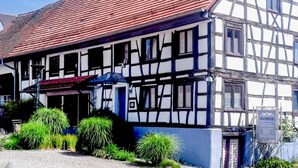 Perinteinen puurunko- ja tiilirakennus, jossa on punainen tiilikatto ja useita ikkunoita.