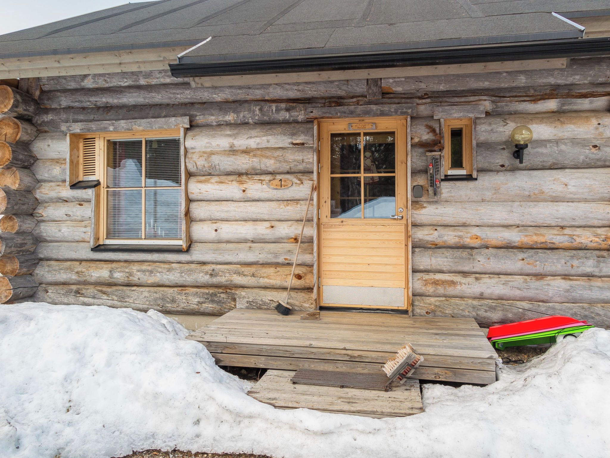 A log cabin with a wooden door, two windows, and a small porch area.