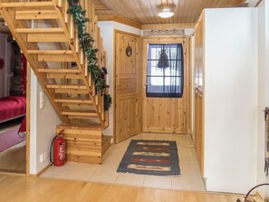 Una escalera de madera con un extintor, una puerta con ventana y un tapete en el suelo.
