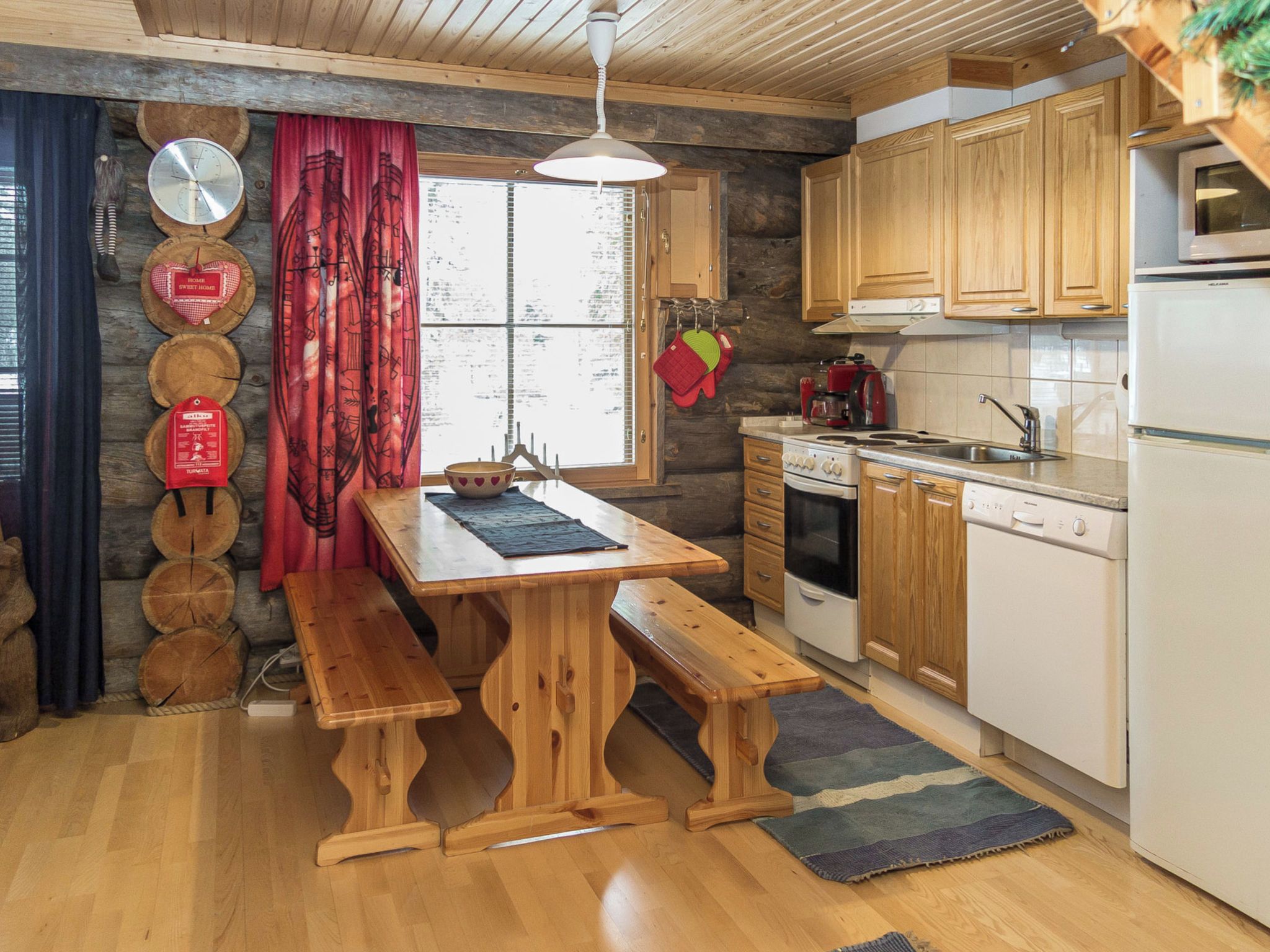 A rustic kitchen with wooden cabinets, a stove, and a refrigerator.