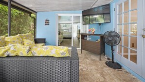 A room with a bed, a fan, and a TV. - Private tropical paradise in the heart of the community! Pool and Welcome Basket (Port Orange)
