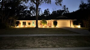 Ein zweistöckiges Haus mit Garage, beleuchteter Außenbeleuchtung und einem gepflegten Rasen.