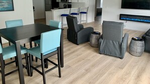 A modern living room with a dining area, kitchen, and a TV mounted on the wall. - Beautifully updated and close to everything!  Yamaha gas cart included! (The Villages)