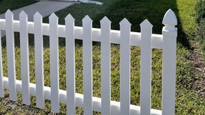 A single-story mobile home with a patio area, a white picket fence, and a lawn. - Beautifully updated and close to everything!  Yamaha gas cart included! (The Villages)
