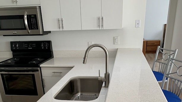 A kitchen with a stainless steel sink, a microwave, and an oven. - Beautifully updated and close to everything!  Yamaha gas cart included! (The Villages)