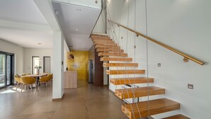 A modern interior with a wooden staircase, a dining area, and a kitchen. - Luxurious home in Jesenice with sauna (Jesenice)