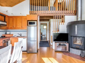 A compact kitchen with wooden cabinets, a stainless steel refrigerator, a microwave, and a stove. - Ski and camp golf casa rocala by Interhome (Nilsiä)