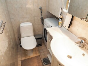 Een kleine badkamer met toilet, wasmachine en wastafel.