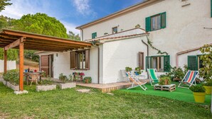 A house with a covered patio, outdoor seating, and potted plants.