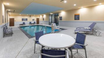 A pool area with a table and chairs, a pool ladder, and a sign indicating no diving.