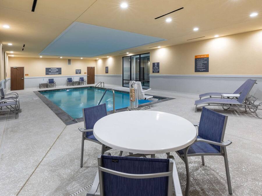 A pool area with a table and chairs, a pool ladder, and a sign indicating no diving.