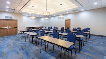 A conference room with multiple tables and chairs, a wooden door, and a sign on the wall.