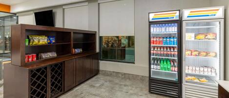 A modern interior with a wooden counter, two refrigerated beverage dispensers, and a window with a view of greenery.