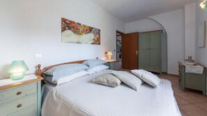 Ein Schlafzimmer mit Bett, Nachttisch, Lampe, Kleiderschrank und einem Bild an der Wand.
