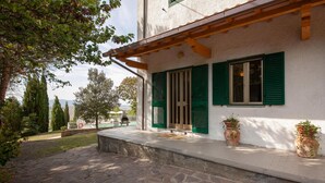 Ein Gebäude mit grünen Fensterläden, einem gepflasterten Eingangsbereich und Blumentöpfen auf der Veranda.