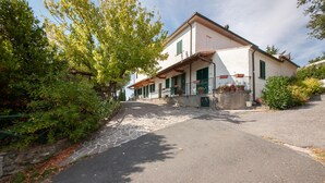 Ein zweistöckiges Haus mit gepflasterter Auffahrt, grünen Fensterläden und Blumentöpfen auf der Veranda.