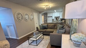Una sala moderna con un sofá, una mesita de centro de vidrio y una lámpara decorativa.