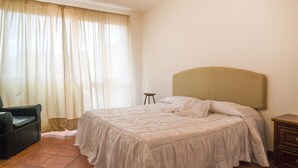 Une chambre à coucher avec un lit, une chaise et une table de chevet.