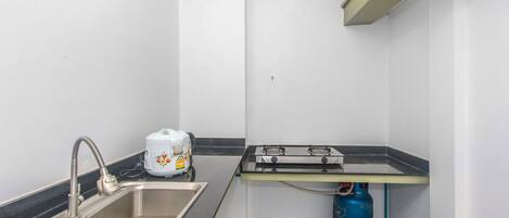 Une petite cuisine équipée d’un évier, d’une cuisinière à gaz et d’un plan de travail.