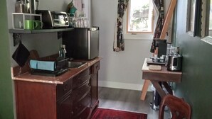 Cocina compacta con encimera de madera, un lavamanos y un ventanal con cortinas florales.