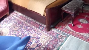 Un dormitorio con una cama grande, una mesita de noche, un banco y dos cuadros en la pared.