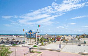 Une zone située au bord de la plage, avec une grande enseigne, un drapeau et un parasol de plage.