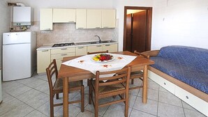 A compact kitchen with a dining table, chairs, and a sofa. - Beach front apartment in Rosolina Mare with house sea view (Rosolina Mare)