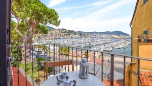 A balcony with a table, a lantern, and a view of a marina with boats and buildings in the background. - Pet friendly apartment in Imperia with WiFi (Imperia)
