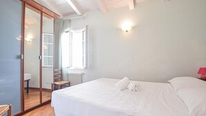 A bedroom with a large bed, a wooden wardrobe, a radiator, and a window with curtains. - Pet friendly apartment in Imperia with WiFi (Imperia)
