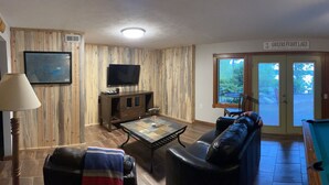Ein Wohnzimmer mit Billardtisch, einer Ledercouch, einem Fernseher und einem Schild mit der Aufschrift 'Greers Ferry Lake'.