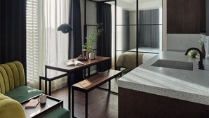 A modern living room with a sofa, a coffee table, a small dining table, and a kitchen area with a sink and countertop. - Staycity London Dalston (London)